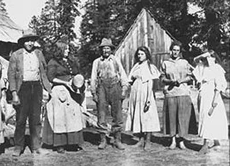 An unidentified group of settlers outside a mountain dwelling